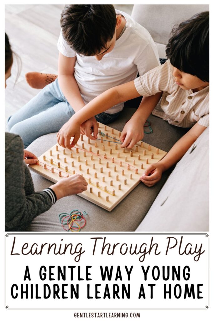 A mother and two young children sit together on a couch, exploring a wooden peg board with rubber bands. The children stretch bands across the pegs as they play and problem-solve, showing a calm, simple example of learning through play at home.